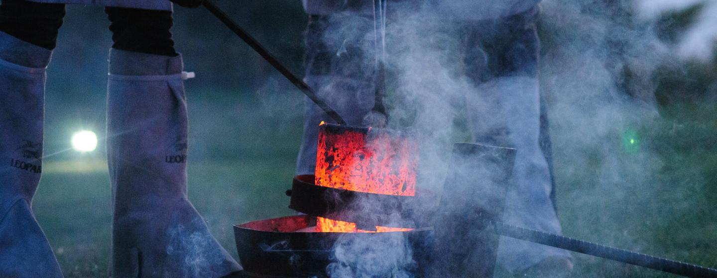 Three people stood round a fire