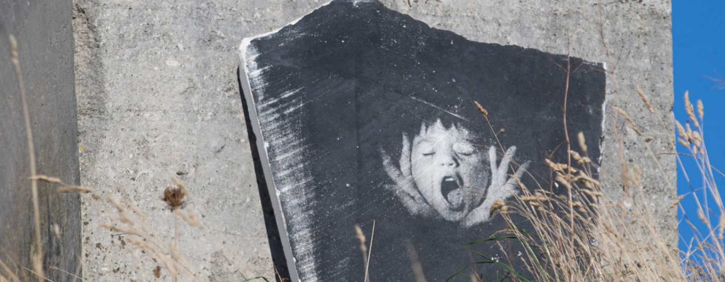 Image of a boys face screaming imprinted on a stone surface