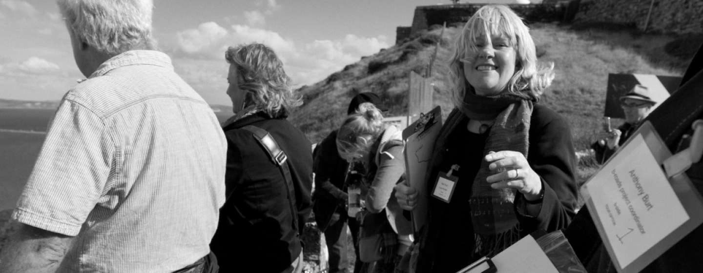 A group of people with clipboards looking out over Portland, a woman with blonde hair smiles into the camera