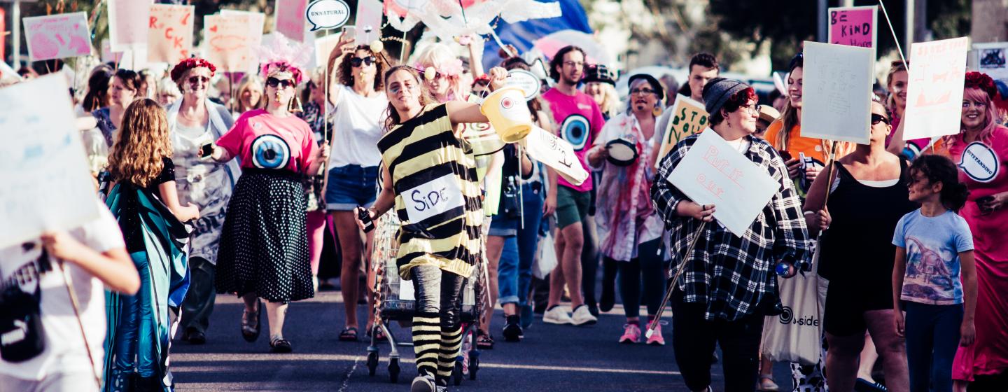 A colourful and lively image of a group of people dressed in fancy dress costume parading through the street at b-side 2021 Photo: Pete Millson