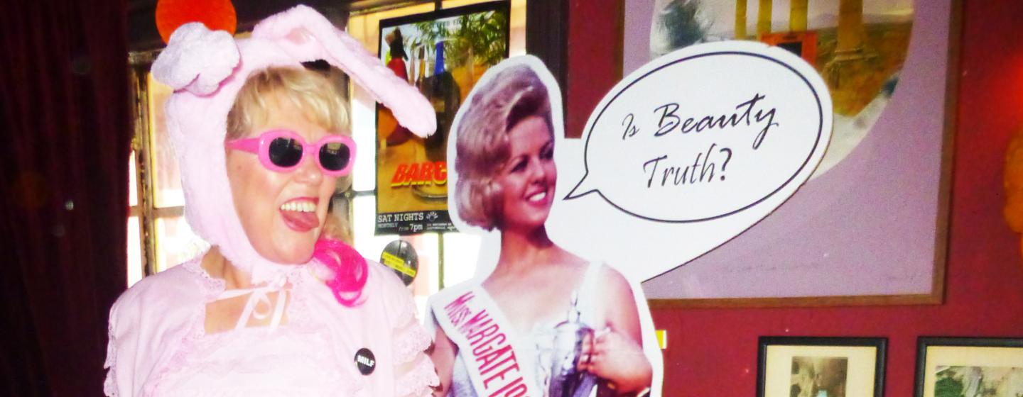 A woman dressed as a rabbit stands next to a cardboard cut out of a beauty queen