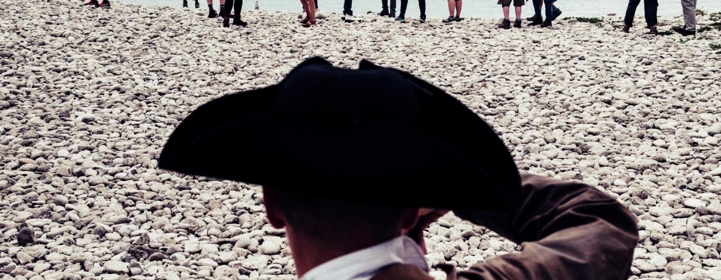 A man with a pirate hat on standing in front of a group of people
