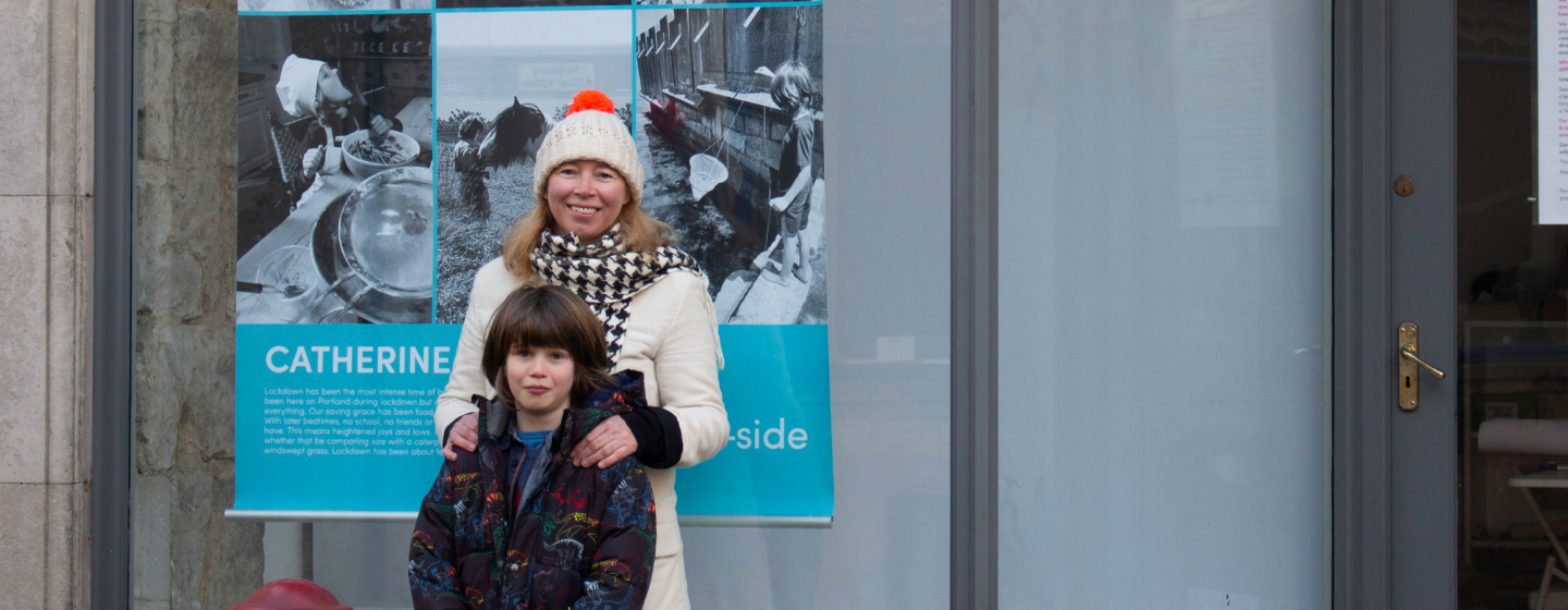 A woman stands with a child in front of a poster