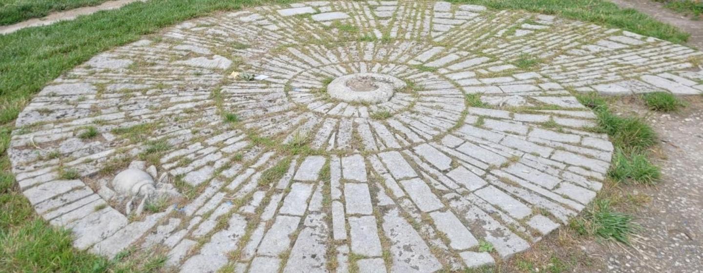 An image of an ammonite laid out in stones in the ground