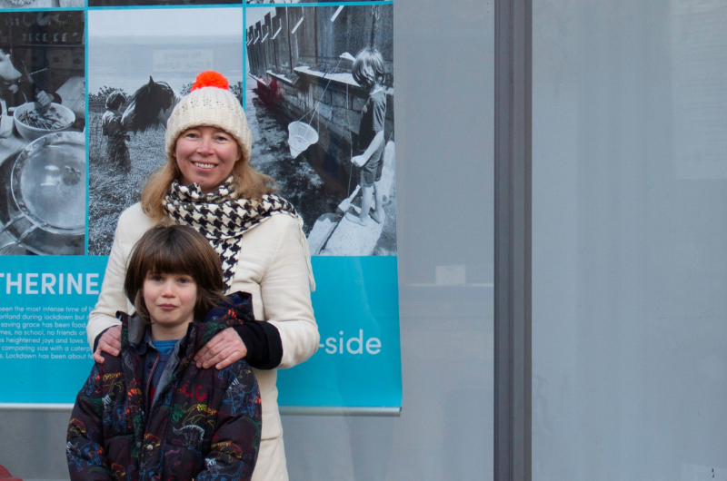 A woman stands with a child in front of a poster